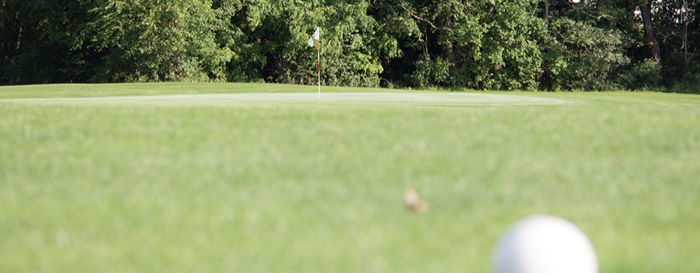 A golf ball resting just off the cup on a Hillcrest green.