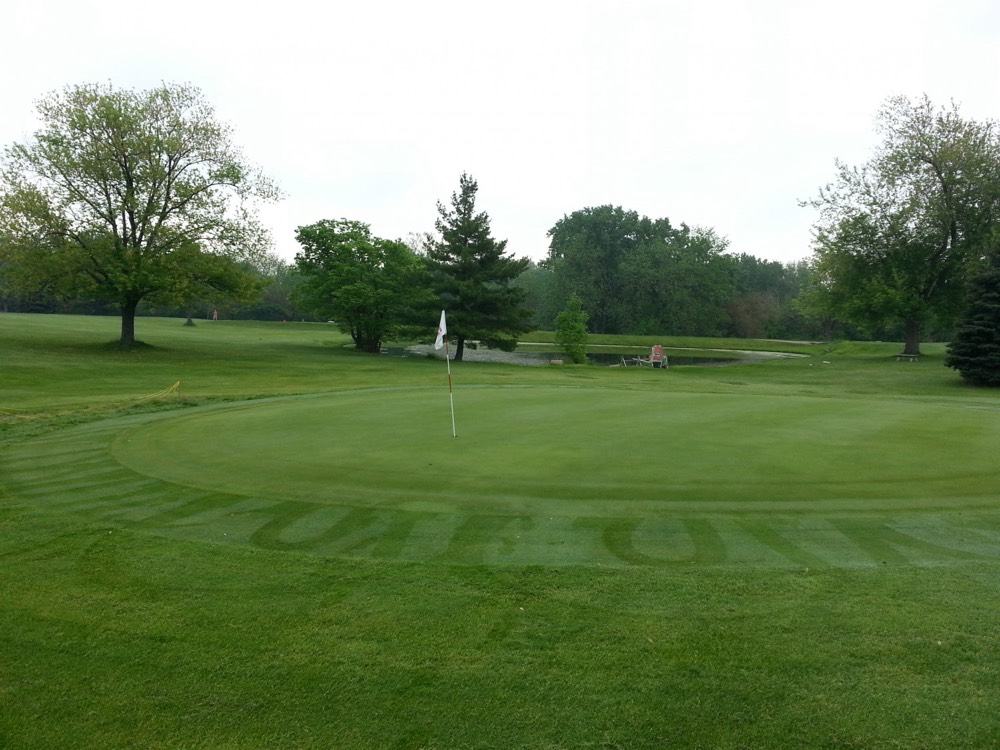 A manicured green at Hillcrest with the flag in, framed by mature trees.